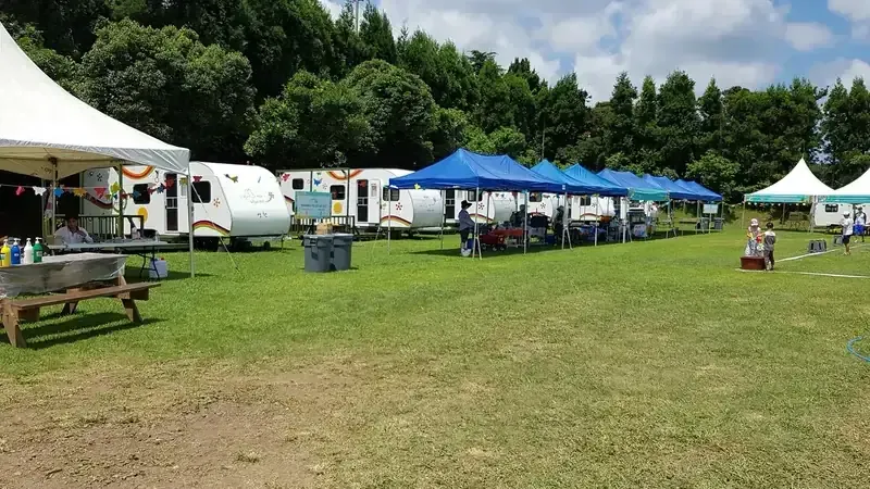 울창한 숲 그늘 아래 잔디밭과 텐트가 설치된 돈내코 야영장