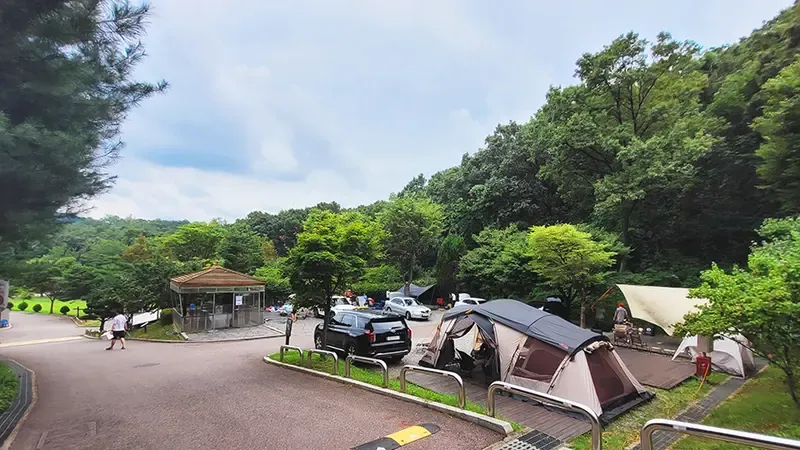 캠핑 사이트 바로 옆 문 앞 주차 공간과 매점 전경